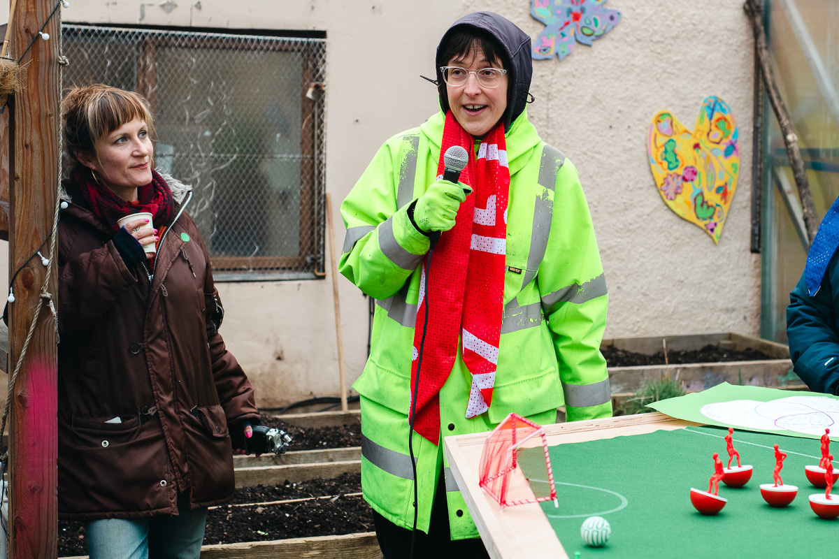 people playing feminist tabletop football with subbuteo-style women and non-binary 3d printed footballers on green felt