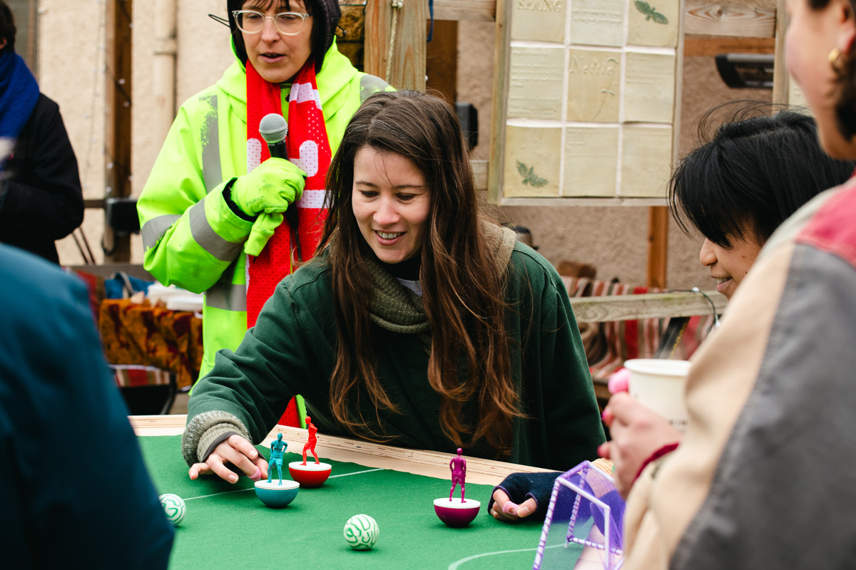 people playing feminist tabletop football with subbuteo-style women and non-binary 3d printed footballers on green felt